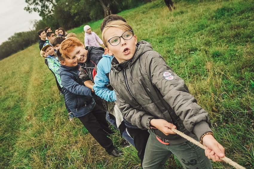 Line of children doing tug of war, all pulling in the same direction