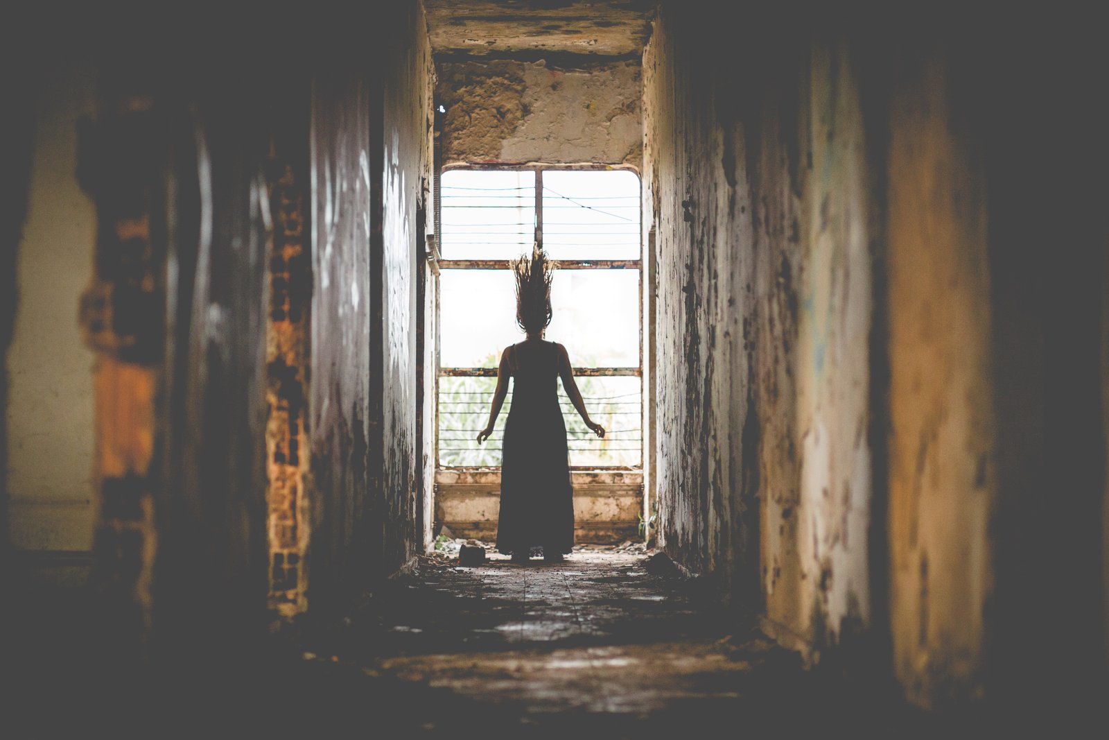 Woman at window at end of corridor with hair standing on end